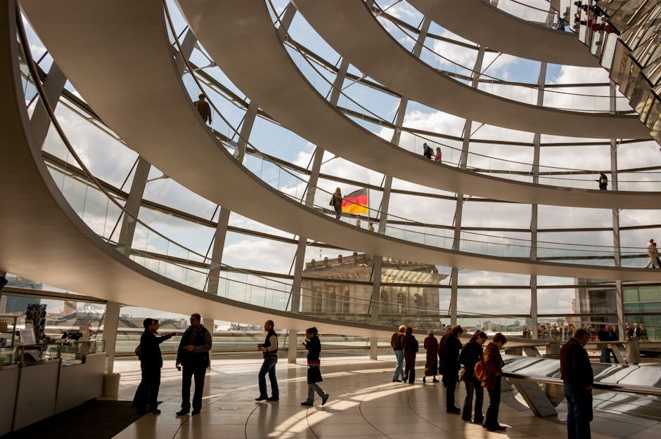Interno del Reichstag a Berlino con visitatori e bandiera tedesca, esempio di architettura moderna e innovazione didattica.