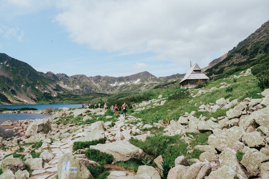 Escursionisti in montagna vicino al lago e rifugio alpino, biodiversità montana per la Giornata Mondiale della Biodiversità Digitale.