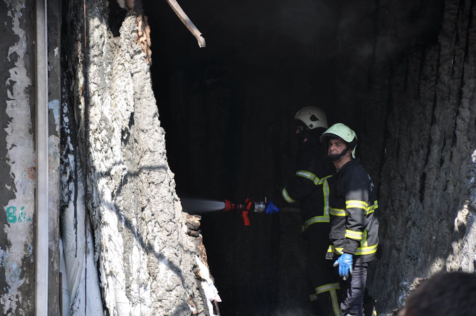 Vigili del fuoco spengono incendio in edificio danneggiato, simbolo della necessità di sicurezza sul lavoro nelle scuole.