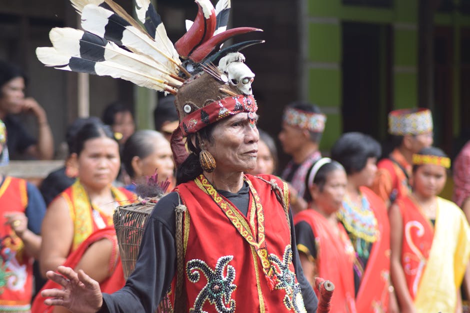 Uomo indigeno con copricapo tradizionale e abiti rossi durante una celebrazione culturale, simbolo di impegno civile e comunità