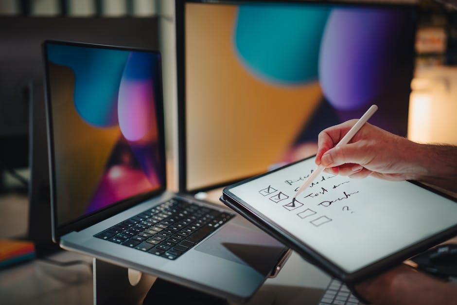 Domanda borsa di studio INPS: persona che compila checklist digitale su tablet con laptop e monitor sullo sfondo