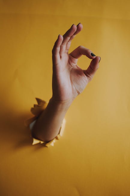 Mano che emerge da sfondo giallo con gesto OK, simbolo di Turnus e accordo, concetto di approvazione e validazione