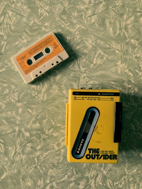 Walkman Sanyo giallo e audiocassetta su sfondo vintage, evocazione anni 80 e tecnologia analogica, contrasto con la modernità digitale.
