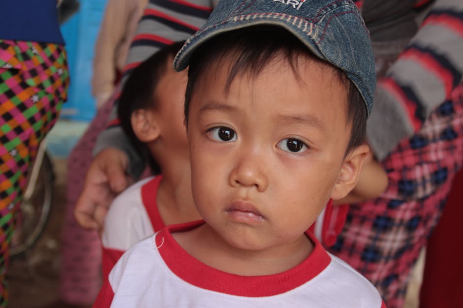 Volto triste di un bambino asiatico con cappellino, riflessione sulla perdita e il dolore dopo l'incidente di Santarcangelo