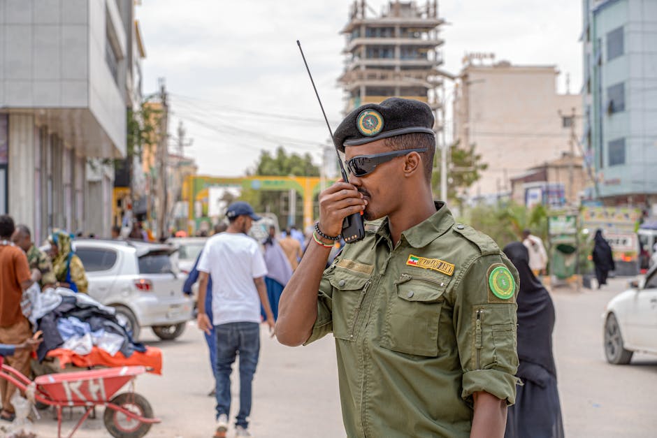 Agente di sicurezza somalo con radio ricetrasmittente in strada affollata, simbolo di protezione e tutela dei lavoratori.