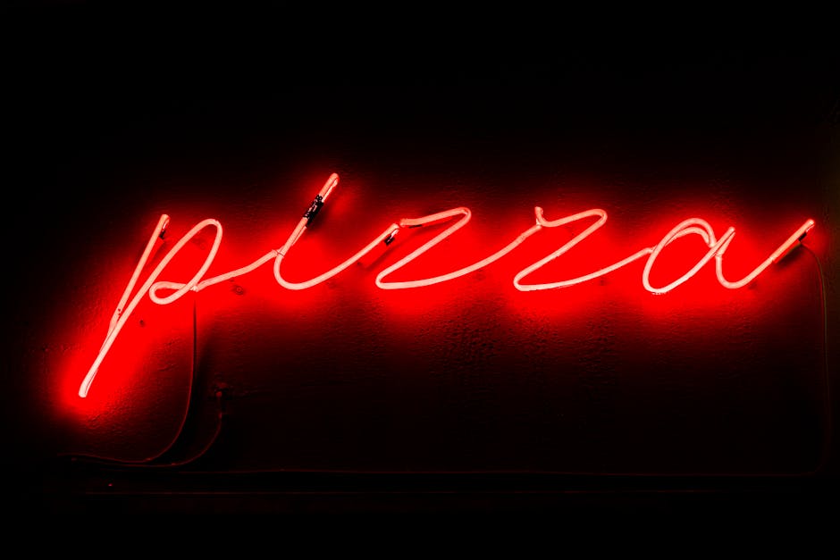 Scritta al neon rossa Pizza che illumina la notte, metafora di scoperte gustose durante la Notte Europea dei Ricercatori