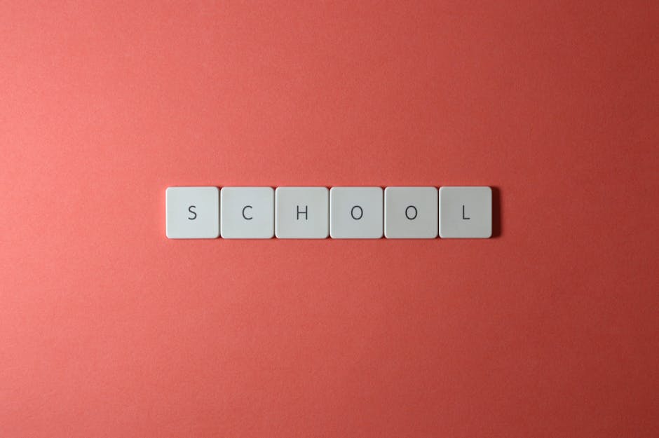 Parola scuola scritta con tessere su sfondo rosso, concetto di psicologia dell'apprendimento e ottimizzazione del processo didattico efficace