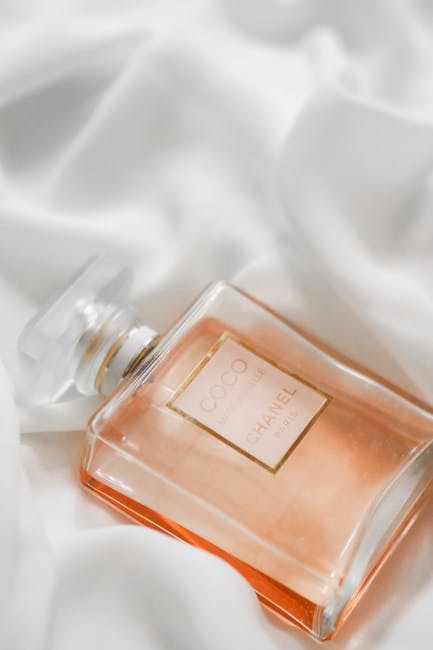 Flacone di profumo Coco Mademoiselle Chanel su sfondo di seta bianca, simbolo dell'eleganza e dell'eredità di Coco Chanel.
