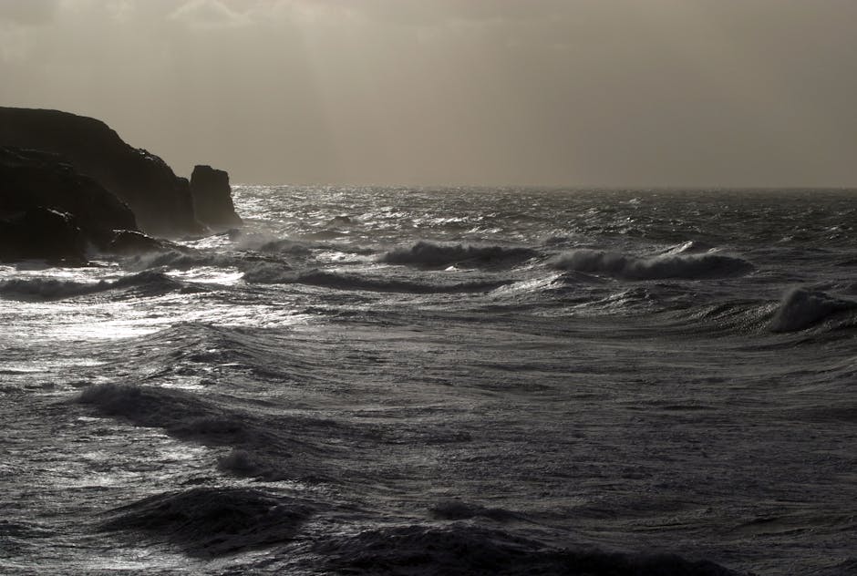 Onde scure si infrangono sulla costa rocciosa, metafora delle sfide economiche superate grazie ai fondi FMOF e CCNI.