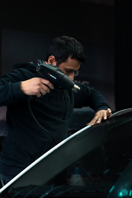 Uomo che usa pistola termica Wurth su superficie nera, conversione Fahrenheit Celsius e applicazioni pratiche spiegate nell'articolo.