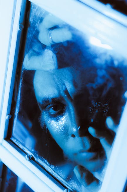 Volto sofferente riflesso in vetro, tonalità blu, evocativo delle difficoltà e delle emozioni durante la Guerra Civile Americana