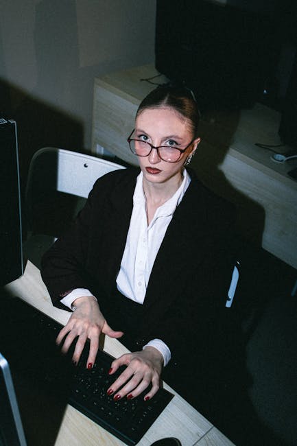 Donna in giacca e occhiali lavora al computer, analisi dati OMC e politiche commerciali internazionali