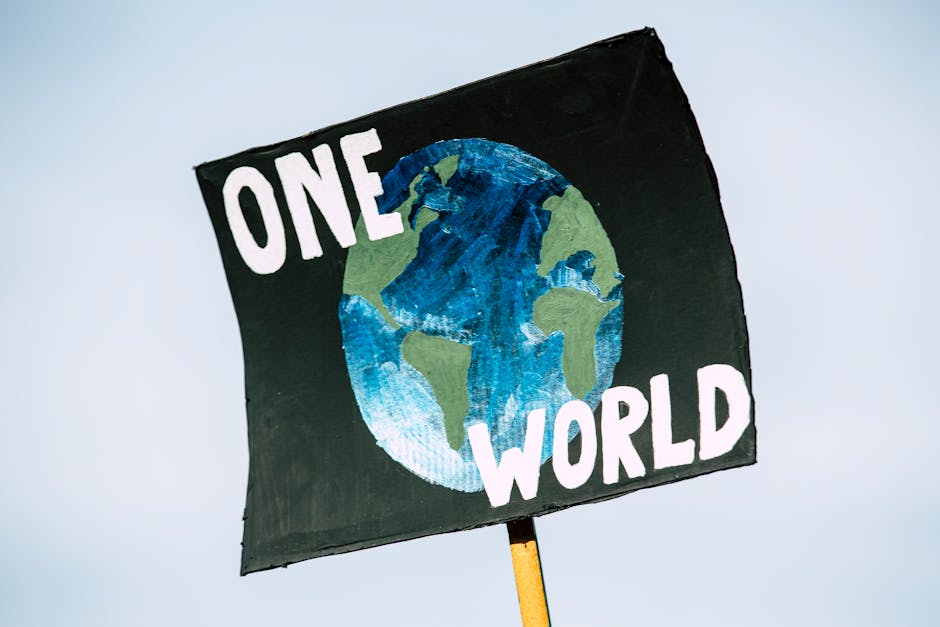 Cartello dipinto a mano con la scritta One World e un globo stilizzato, simbolo di unicità e connessione globale per distinguersi online.