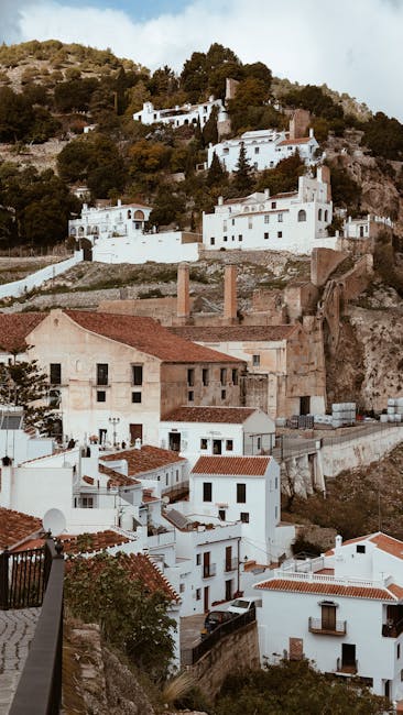 Paesaggio urbano andaluso con case bianche e tetti rossi arroccate sulla collina, tipico borgo spagnolo immerso nella natura mediterranea.