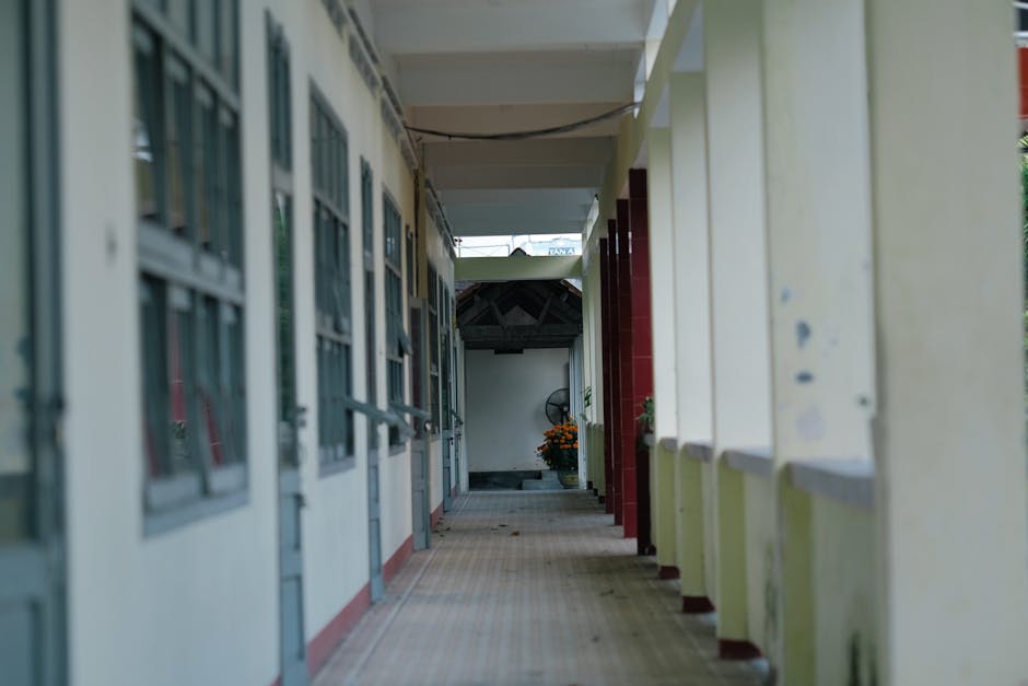 Corridoio scolastico vuoto con aule e pilastri: riflessione sulla Legge di Bilancio e le sfide per l'istruzione degli studenti svantaggiati