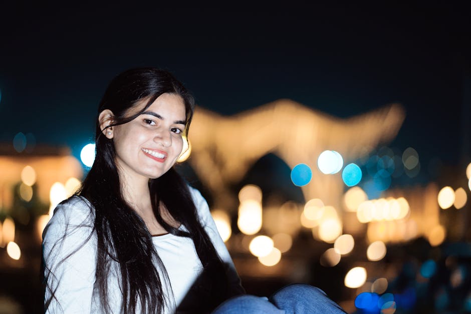 Giovane donna sorridente con luci notturne sullo sfondo, simbolo di speranza e futuro plasmato dall'istruzione e dalla scuola