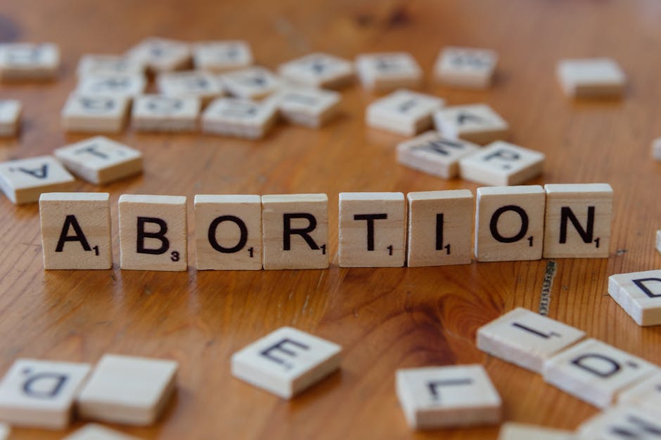 Aborto scritto con tessere di Scrabble su tavolo di legno, simbolo di scelte difficili e dibattiti etici legati alla medicina.