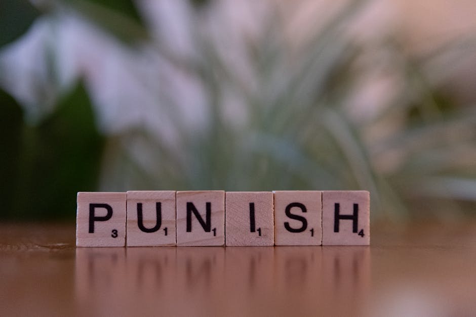 Punizione a scuola: tessere di legno con la parola PUNISH, riflesso su una superficie lucida. Contrasto con il coinvolgimento scolastico.