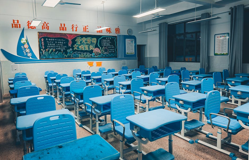 Aula scolastica vuota con banchi blu, lavagna e scritte in cinese, spazio di apprendimento per l'IA e l'agency docente