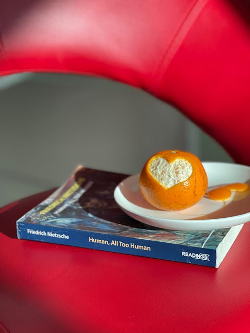 Angolo di lettura con libro di Nietzsche e arancia intagliata a forma di cuore, metafora della chiarezza e definizione in filosofia