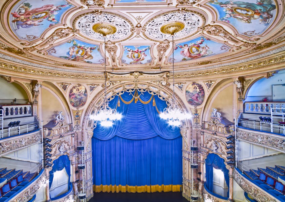 Interno del Teatro Brancati di Catania, luogo del debutto di Tuccio l’eterno, con sipario blu e decorazioni artistiche.