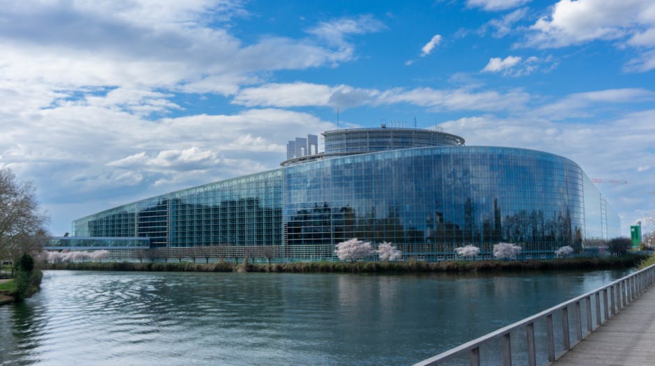 Edificio del Parlamento Europeo con fiume e cielo nuvoloso, sede della decisione su Qwant come motore di ricerca predefinito per la scuola