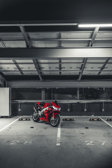 Motocicletta rossa parcheggiata in un garage sotterraneo, simbolo di opportunità economiche ATA e preparazione alla prova finale