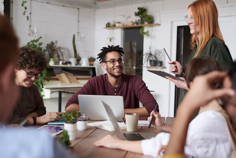 Gruppo di persone diverse collabora a un tavolo con laptop, promuovendo dialogo culturale e innovazione in un ambiente di lavoro inclusivo.