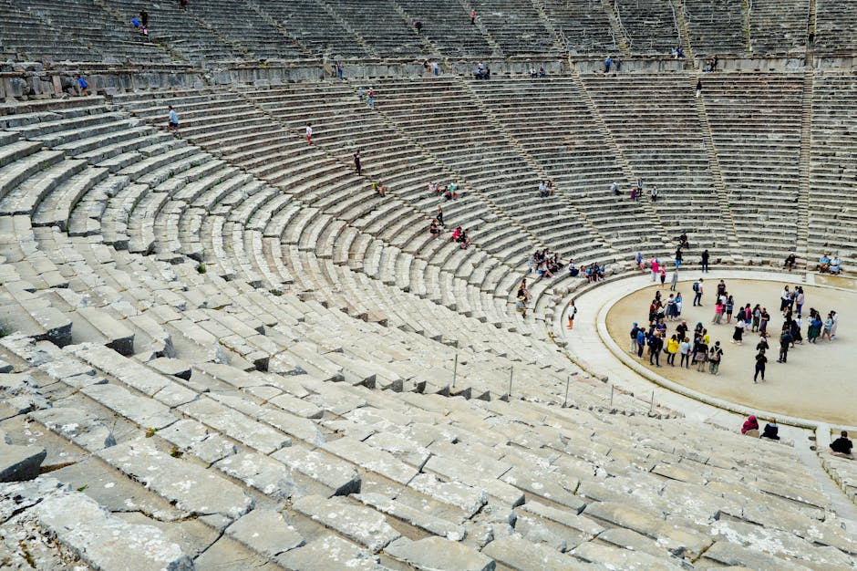 Anfiteatro romano antico con gradinate in pietra e visitatori, simbolo di valori universali e dell'eredità classica di Virgilio