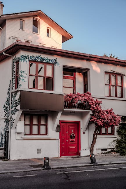 Casa con porta rossa e albero fiorito, simbolo di accoglienza e scambio culturale per ErasmusDays 2025.