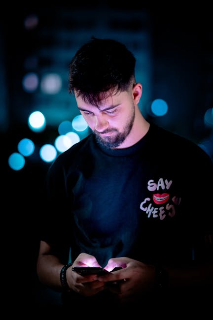Giovane uomo concentrato sull'uso dello smartphone, simbolo della dipendenza digitale tra gli studenti nel Safer Internet Day 2026.