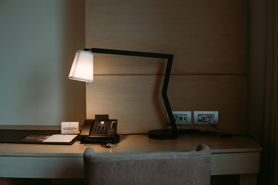 Camera d'albergo con scrivania, lampada e telefono: rischio elettrico per studenti in gita scolastica, responsabilità del docente.