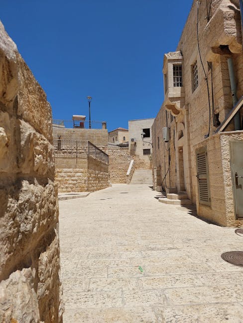 Architettura urbana in pietra chiara, vicolo soleggiato con edifici storici. Aumenti salariali docenti e ATA: focus sul rinnovo contrattuale.