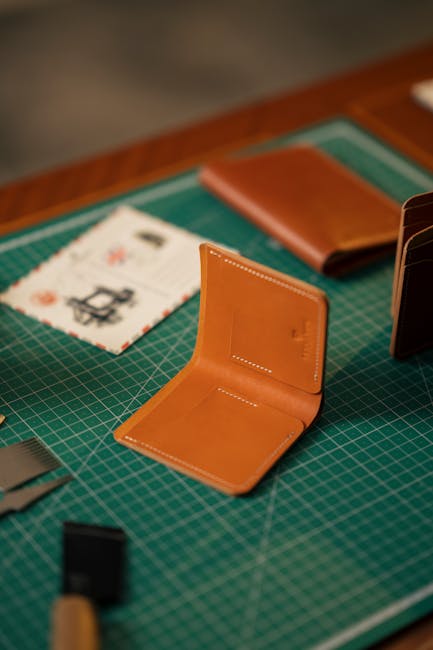 Portafoglio in pelle artigianale aperto su piano di lavoro verde, simbolo di accoglienza e cura del dettaglio nell'ospitalità.