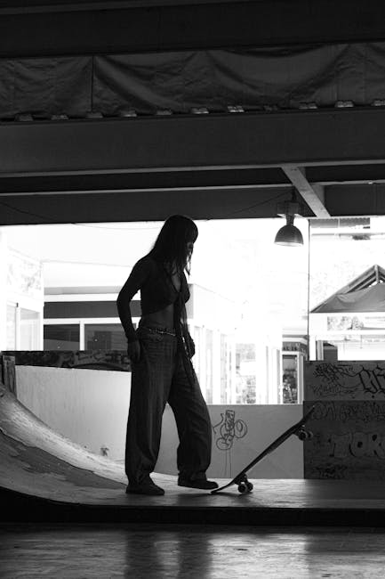 Immagine in bianco e nero di una giovane donna con uno skateboard in uno skatepark, evocativa di solitudine e isolamento, pertinente al tema della persecuzione.