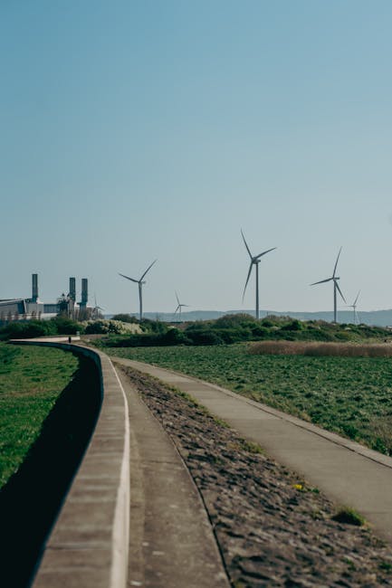 Paesaggio con turbine eoliche e centrale elettrica: un futuro energetico sostenibile discusso al G7. Transizione ecologica e fonti rinnovabili.