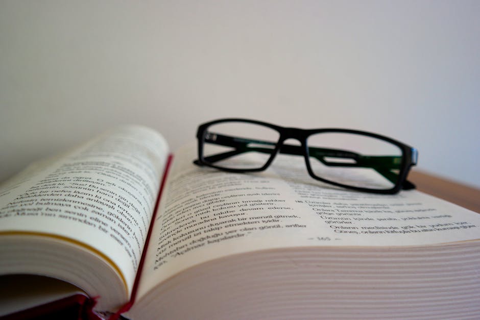 Libro aperto con occhiali da lettura, simbolo di studio e materiali didattici per l'istruzione scolastica promossi dall'Accademia della Crusca.