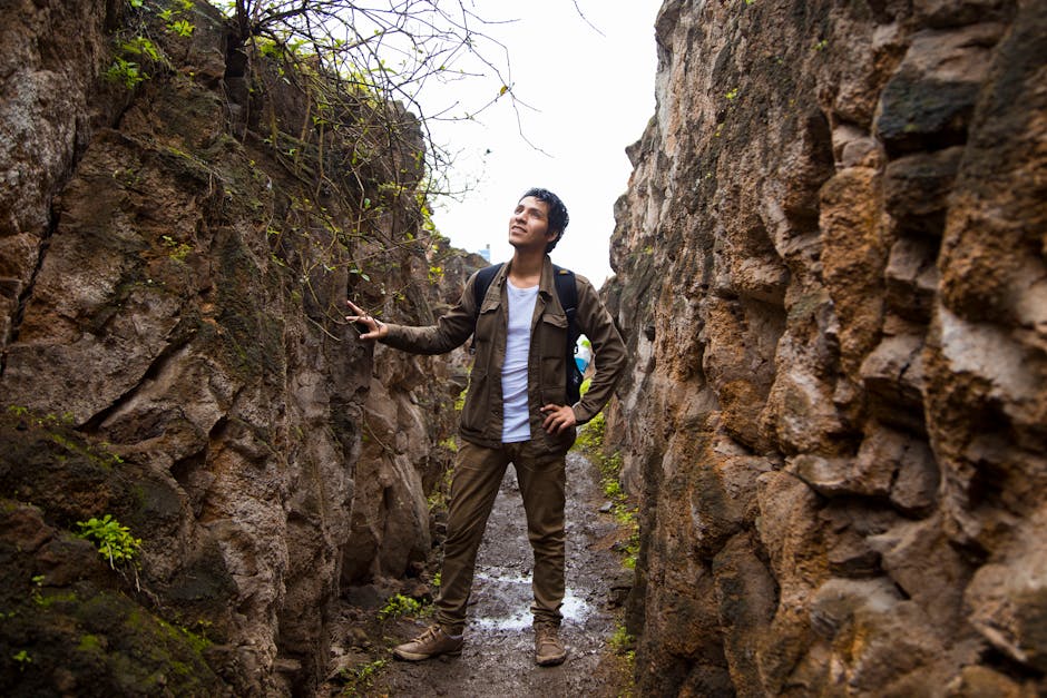 Viaggiatore esplora canyon roccioso in America, immerso nella natura e storia del continente americano durante un'avventura culturale.