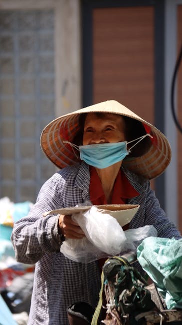 Donna asiatica sorridente con cappello conico e mascherina, simbolo di resilienza e speranza per il welfare del personale scolastico.