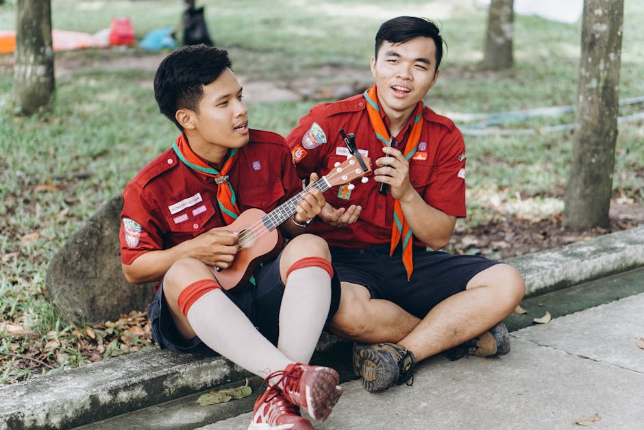 Due amici scout suonano l'ukulele all'aperto, un'attività musicale stravagante e coinvolgente per sorprendere i tuoi amici.