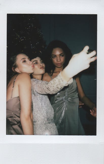 Tre amiche in abito da sera scattano un selfie insieme, sorridendo e divertendosi, durante una festa o un evento speciale.