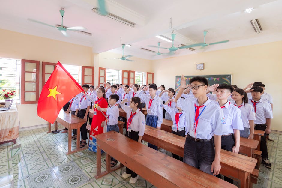 Studenti vietnamiti in uniforme scolastica salutano la bandiera, simbolo di patriottismo e impegno civico, ispirando i valori promossi dagli Alpini.