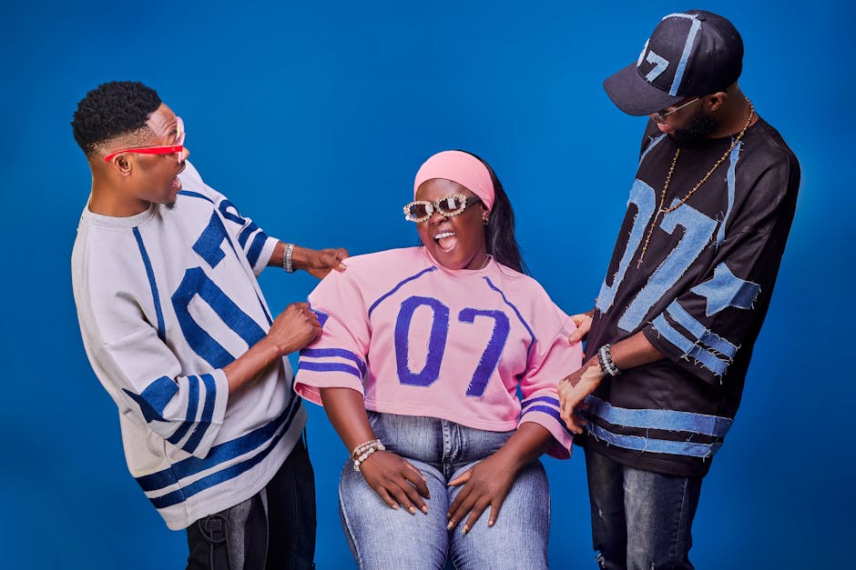 Tre amici in posa con abiti sportivi e occhiali da sole su sfondo blu, espressioni vivaci e look coordinati per un'immagine di gruppo.