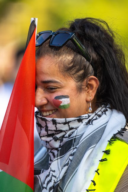 Donna sorridente con bandiera palestinese dipinta sul viso e kefiah, simbolo di solidarietà e diritti umani