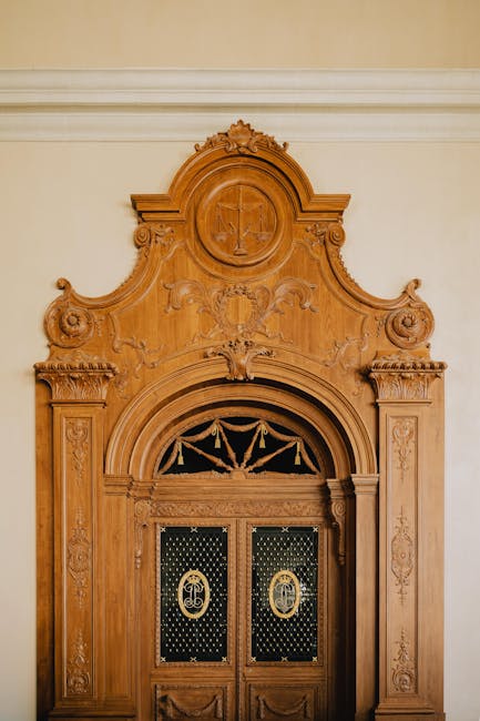 Porta in legno intarsiato con simbolo della giustizia, richiamo al contributo giuridico di Ernesto Maria Ruffini. Dettagli artistici e simbolici.