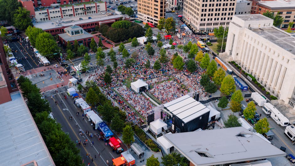 Immagine aerea di una folla numerosa al Festival Orientamenti di Genova, con stand e palco per eventi, testimonianza del grande afflusso di pubblico.