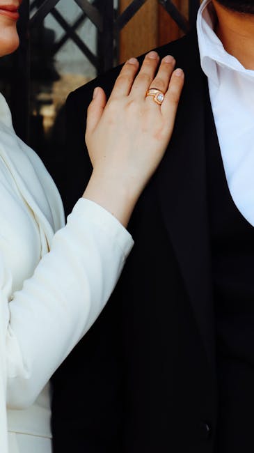 Mano femminile con anello su spalla maschile in segno di supporto e collaborazione nella scienza per le donne