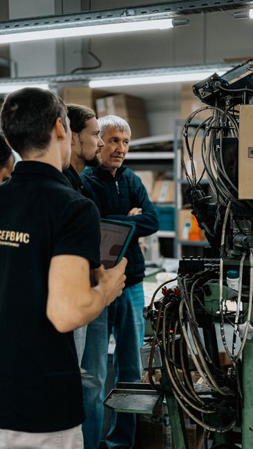 Team di professionisti analizza un macchinario industriale con tablet, simulando la gestione di interpelli e supplenze scolastiche 2026/27