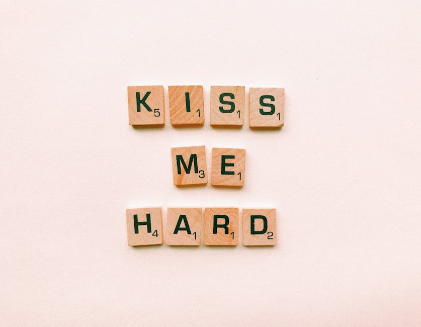 Ispirazione sentimentale: parole d'amore 'Kiss me hard' scritte con tessere di Scrabble, metafora dell'educazione emotiva e passione per l'amore.