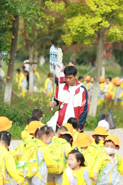 Docente con cartello e bambini in gita scolastica: focus sulle ferie e permessi dei docenti, diritti e normative.